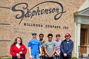 SEED Program: Wilson Community College students posing in front of the Stephenson Millwork building sign during their tour.