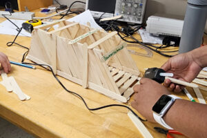 SEED Program: Close-up of a student working on their popsicle stick bridge from the class project.