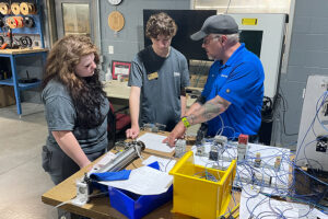 SEED Program: Two students and an instructor reviewing bridge plans together.